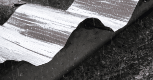 Cinta asfáltica impermeabilizante Texsatape de Texsa aplicada en tejado ondulado bajo lluvia, con terminación de foil aluminio expuesto al sol y a la intemperie